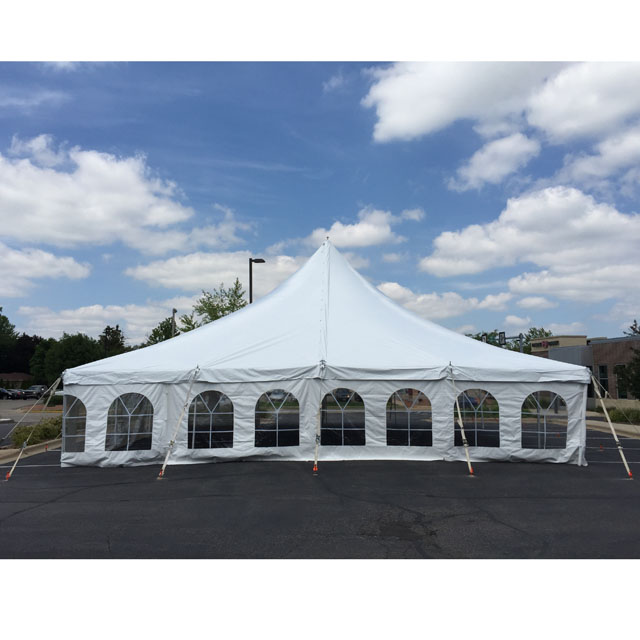 White pole tent with clear windows, set up on black-top concrete.