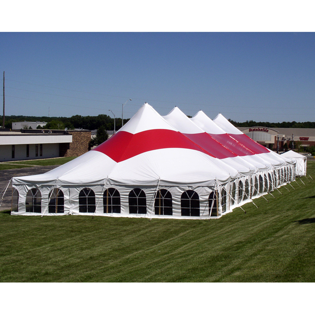 White pole tent with a red stripe and clear windows set up in a grass field.