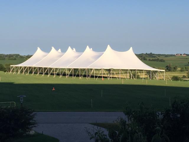 Large white pole tent set up at an outdoor venue on a sunny day.