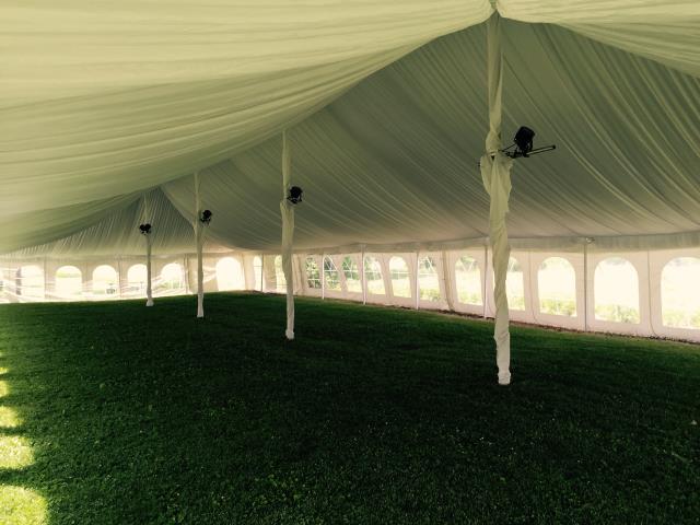 White pole tent with outdoor lighting on a lawn.