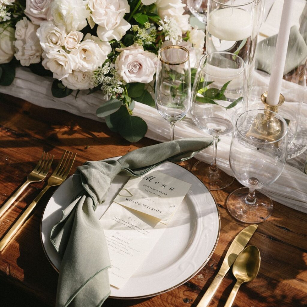Wooden table rental set for table number 7 at a wedding dinner reception, decorated with floral arrangements and menus.