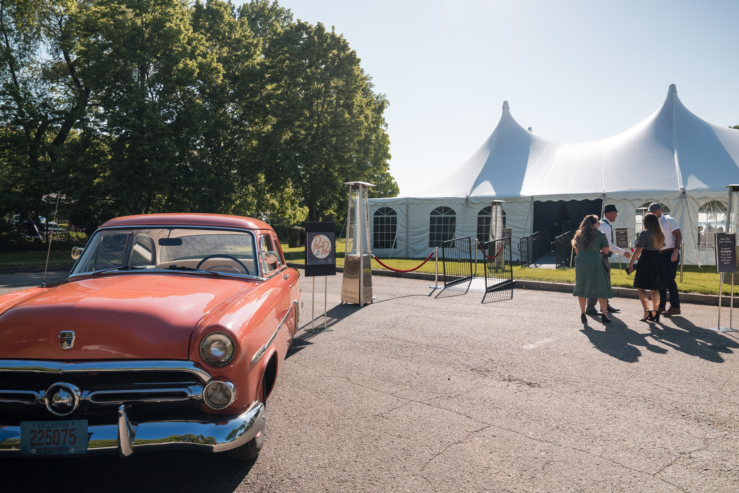 Vintage orange ford parked in front of a pole tent rental for a picnic in the park event in Madison, WI.